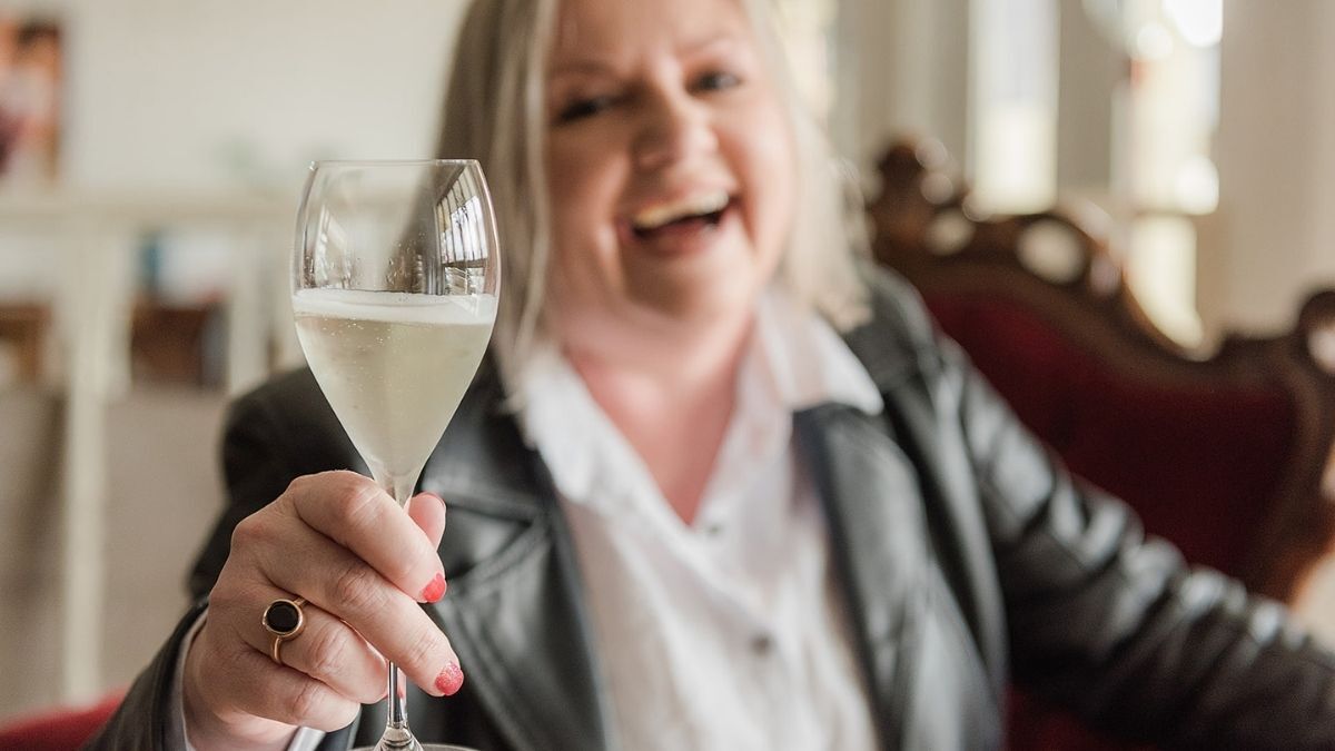 Mell Millgate, founder of Starfish Marketing in Albury Wodonga, smiling and raising a glass of sparkling wine in a celebratory toast.
