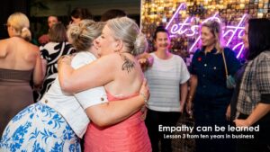 Two women embracing at a business event, representing connection and empathy in client relationships and communication.