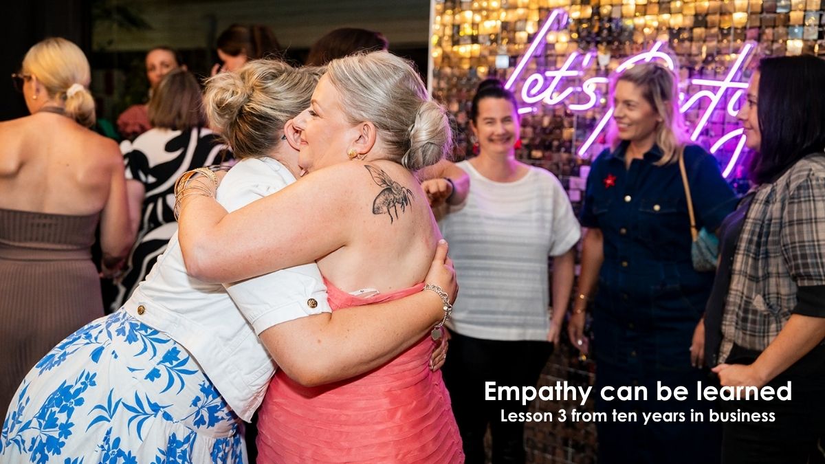 Two women embracing at a business event, representing connection and empathy in client relationships and communication.